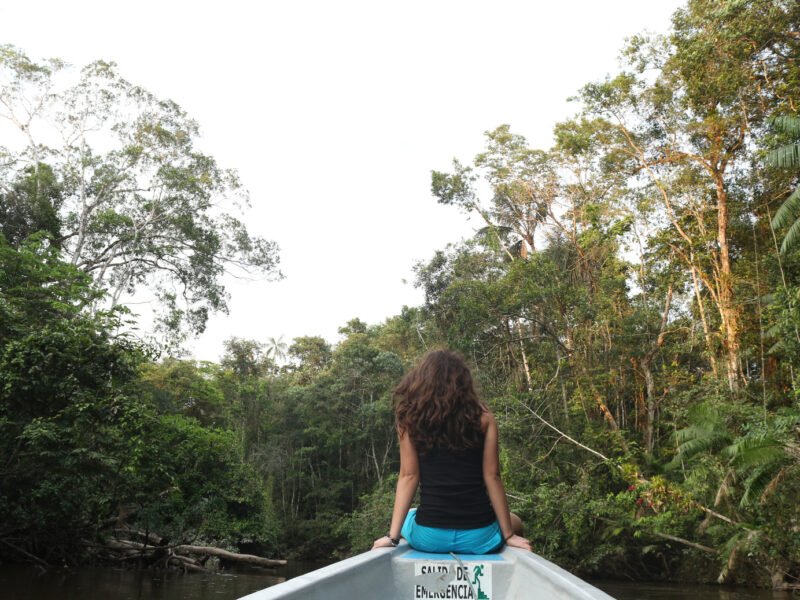 Traveler enjoying the river breeze at the bow of a canoe in Cuyabeno