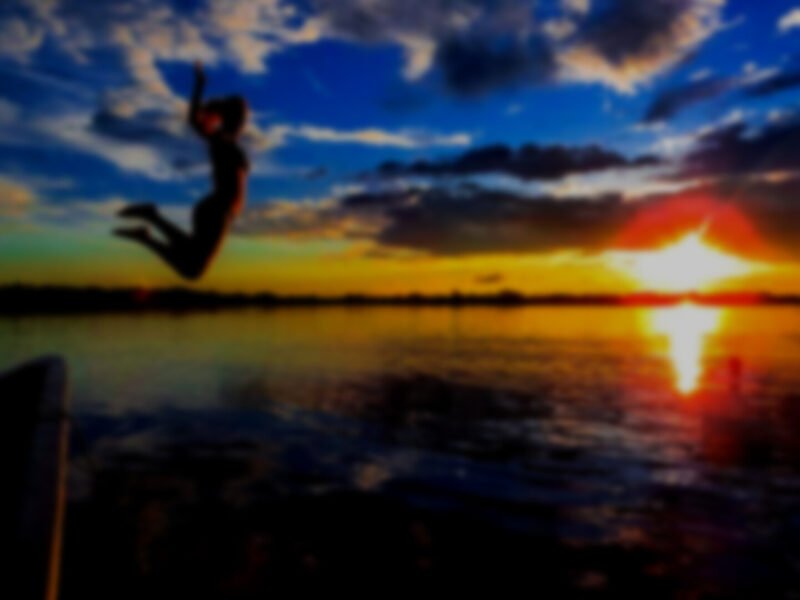 Traveler jumping into the Laguna Grande at sunset, Cuyabeno