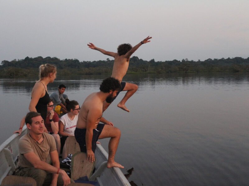 Travelers jumping into the lagoon at sunset, Cuyabeno